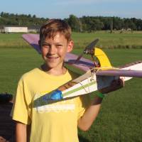 yellow team student poses with his plane during flight night